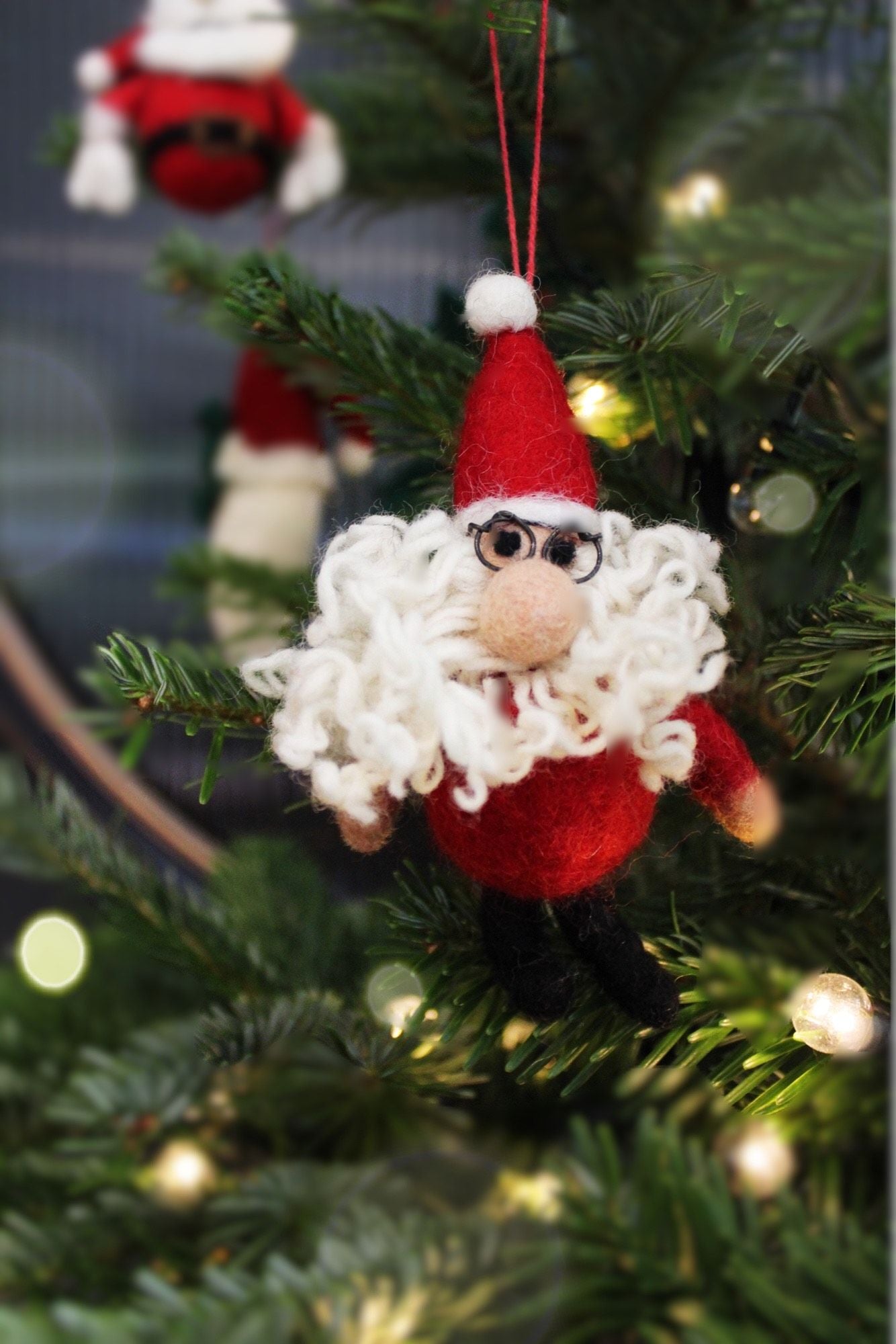 Curly Santa by Felt So Good has a woolly perm and wire glasses. A handmade wool felt Christmas tree decoration, sustainable, fair trade and festive.